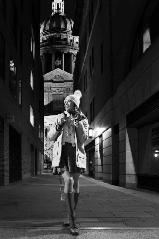 Black and white image of a joyful woman in front of St Paul's Cathedral in London exuding happiness and radiance in this timeless portrait.